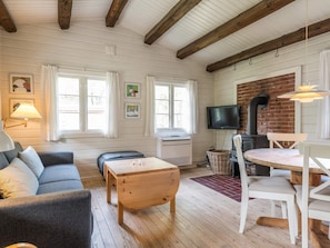 A cozy living room with a sofa, wooden coffee table, and a dining area with a table and chairs.