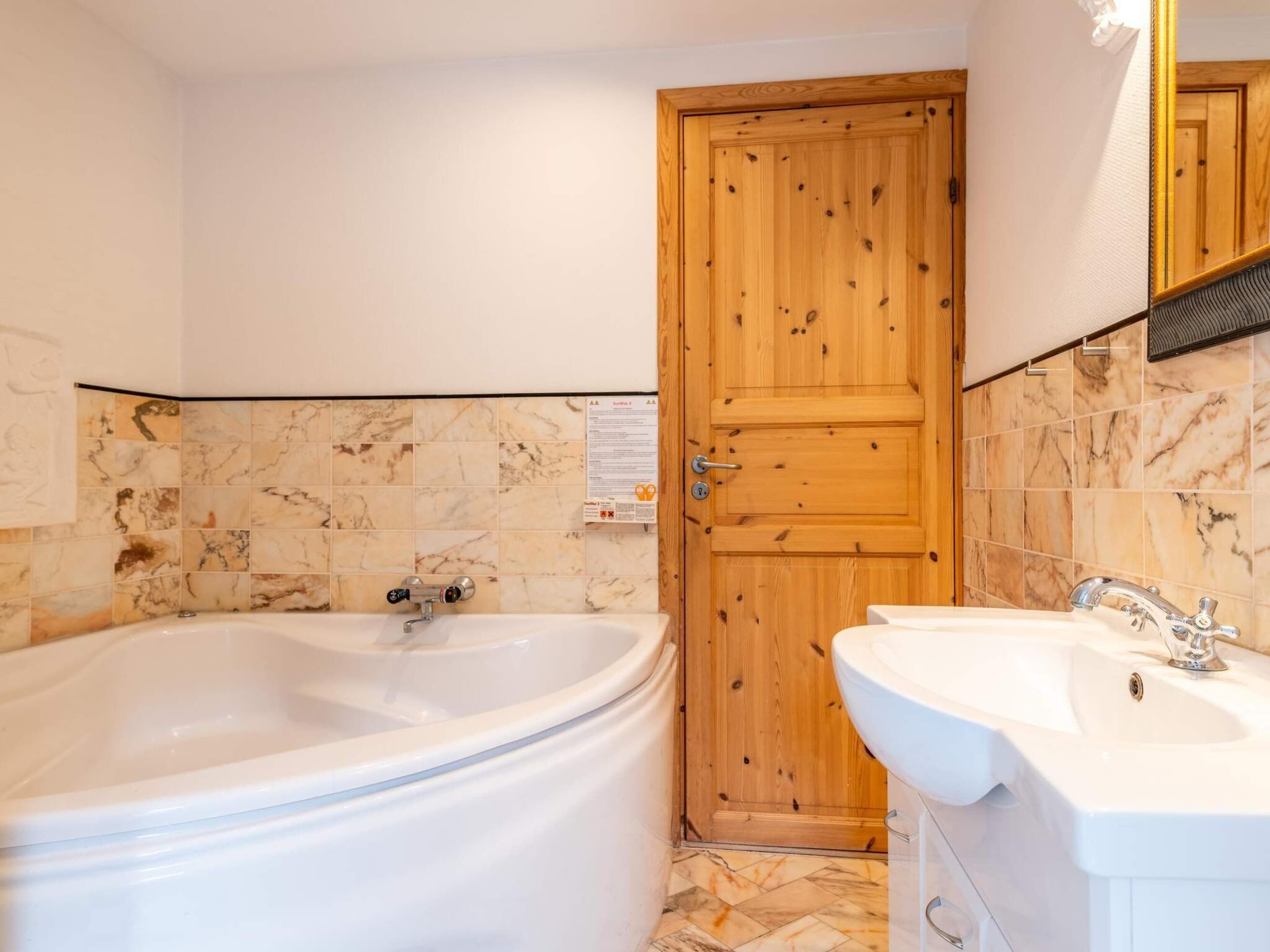 Une salle de bain avec une porte en bois, une baignoire et un lavabo.