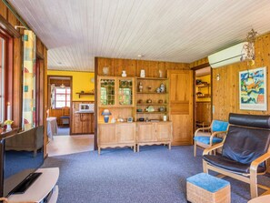 Een knus interieur met houten wanden, een blauw tapijt, een televisie, een bank en een eettafel.