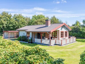 A two-story house with a covered porch, a chimney, and a well-maintained lawn.