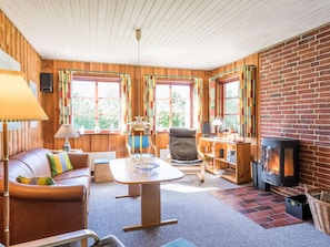 A cozy room with a fireplace, wooden walls, a sofa, a table, and a chair.