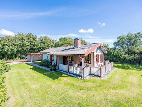 A single-story house with a porch, a chimney, and a well-maintained lawn.