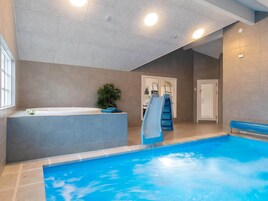 Una piscina cubierta con tobogán, jacuzzi y escalera que lleva a una puerta.
