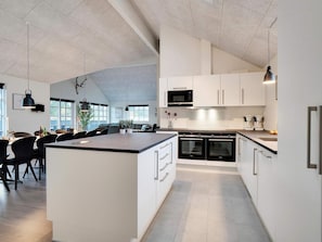 A modern kitchen with white cabinetry, black appliances, and a central island.