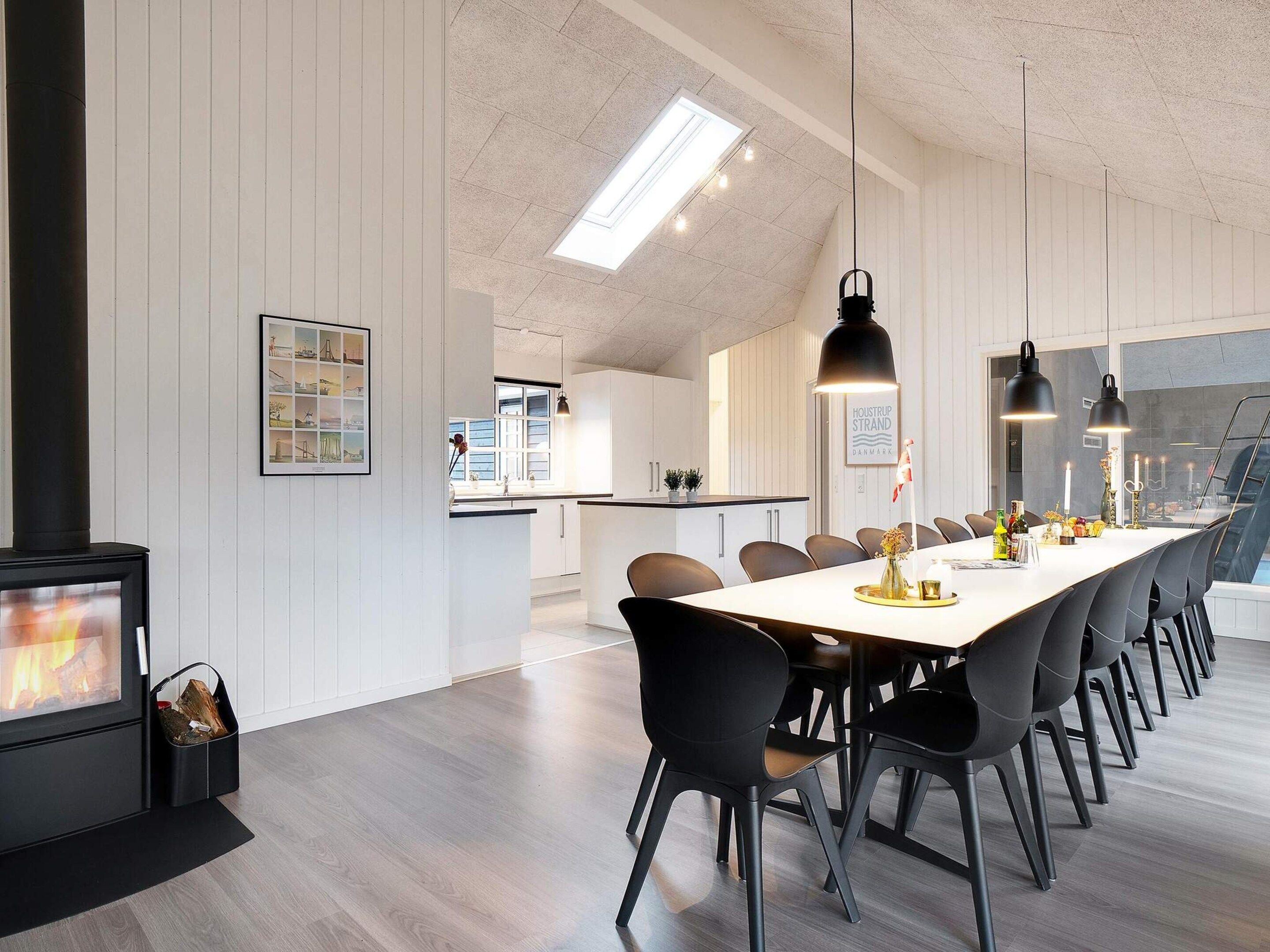Un espace de salle à manger moderne avec une longue table, des chaises et des luminaires suspendus.