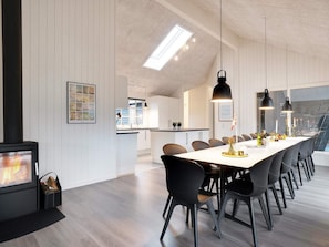 A modern dining area with a long table, chairs, and pendant lighting.