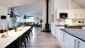 Een moderne keuken met witte kasten, een groot eiland en een ingebouwde kookplaat.
