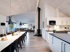 Una cocina moderna con armarios blancos, una isla grande y una estufa empotrada.