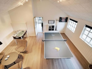 A room with a ping pong table, a foosball table, and a dartboard.