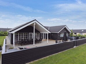 A modern house with a covered patio area featuring outdoor seating.