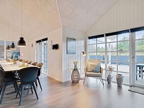 Un espace de salle Ă manger moderne, avec une longue table, des chaises, des luminaires suspendus et une vue dĂ©gagĂ©e grĂące Ă de grandes fenĂȘtres.
