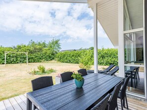 A covered outdoor dining area with a table and chairs, a potted plant, and a soccer goal in the background. - Holiday Home in Tarm (Tarm)