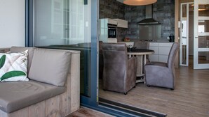 A modern living room with a glass partition, a sofa, and a dining area with chairs and a table. - Apartment in Veere With Lake Views & Marina (Kamperland)