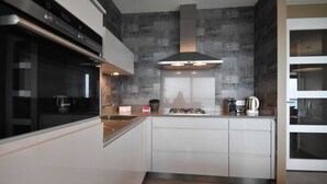 A modern kitchen with a built-in oven, a gas stove, and a stainless steel range hood. - Apartment in Veere With Lake Views & Marina (Kamperland)