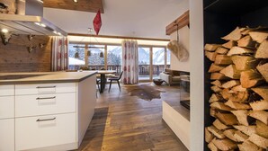 A modern kitchen with wooden accents, a dining area with a view of mountains, and a fireplace with wood logs. - Inviting Chalet in Neukirchen near Wildkogel Ski Arena (Neukirchen am Grossvenediger)