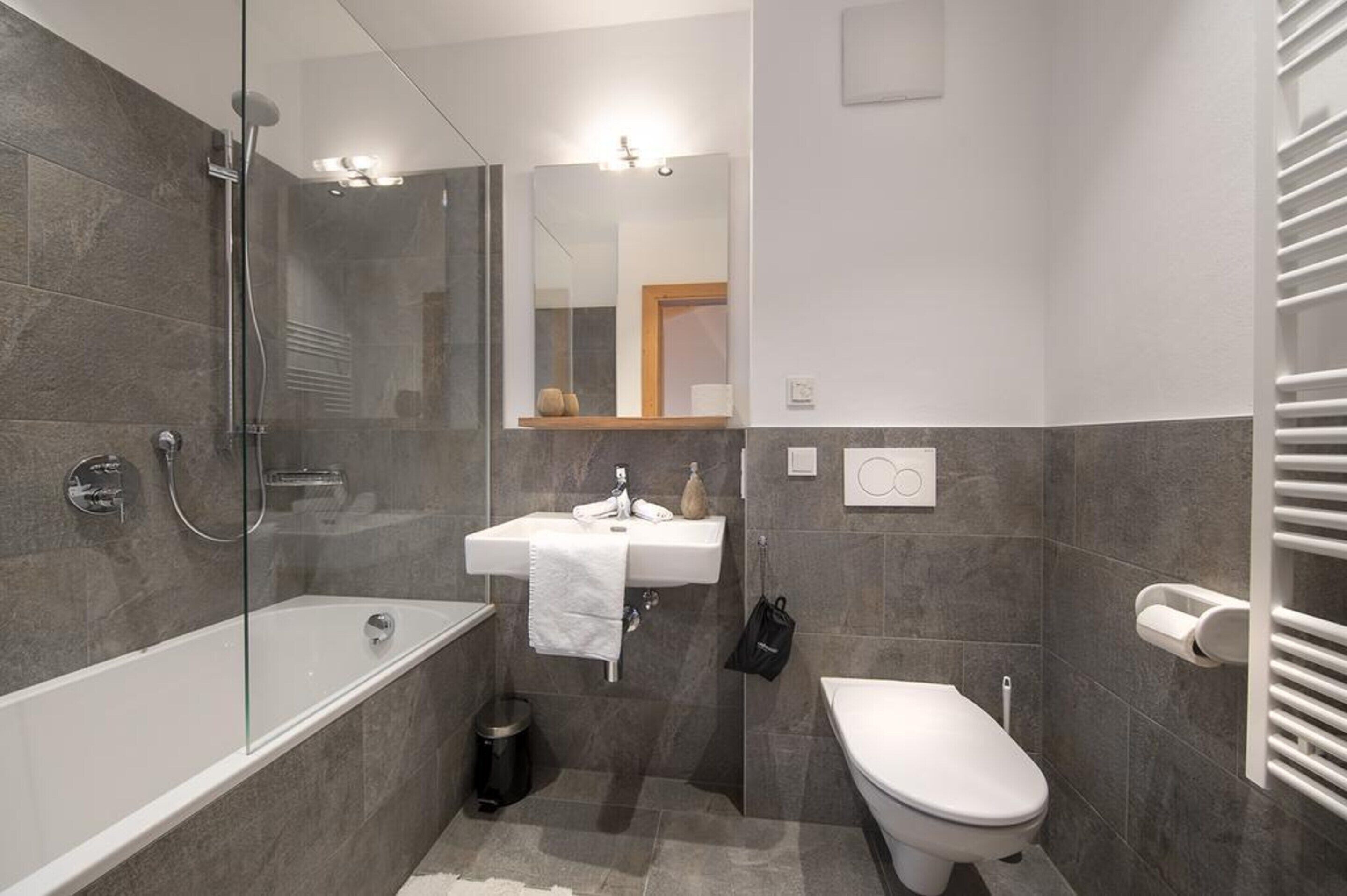 A modern bathroom with a glass-enclosed shower, a white sink, and a toilet.