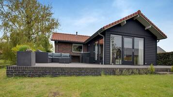 Una casa moderna con un patio, un amplio ventanal corredera y una chimenea de ladrillo.