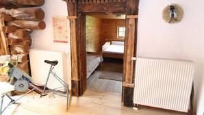 Quarto rústico de madeira com uma cama, um radiador e uma bicicleta.