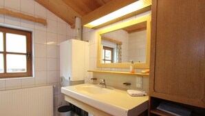 A bathroom with a white sink, wooden cabinets, a mirror, and a window.