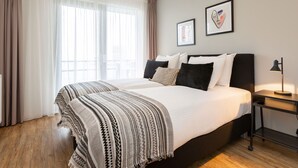 A hotel room with a large bed, a bedside table with a lamp, and two framed pictures on the wall. - Sea-view Apartment in Den Haag near Beach (The Hague)