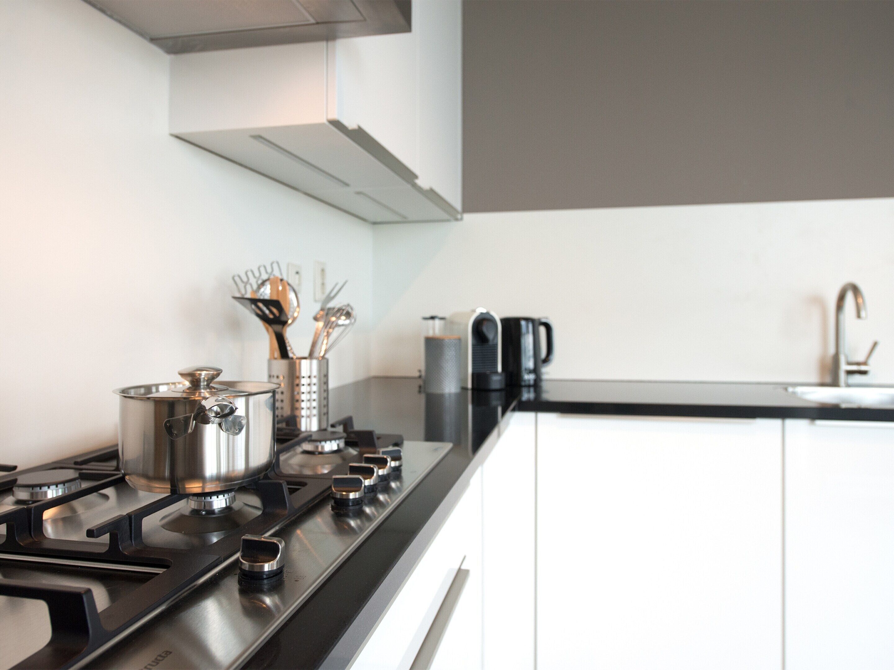 A modern kitchen with a gas stove, pots, a coffee maker, and a knife block.