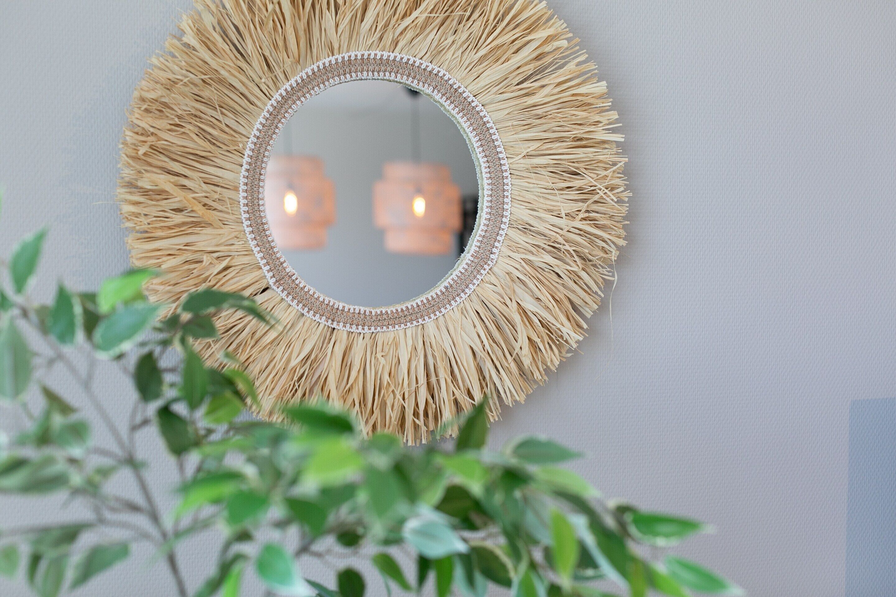 A round mirror with a straw-like frame on a wall.