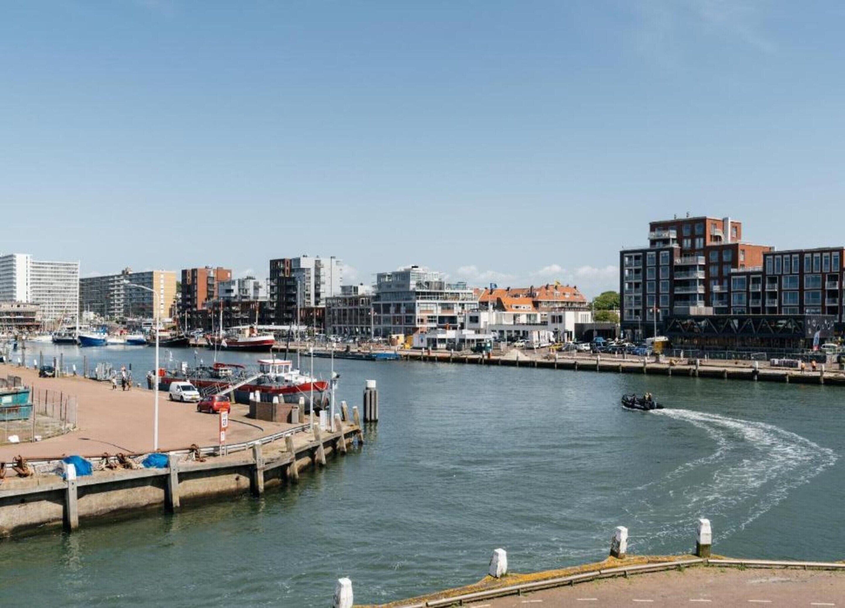 Un puerto deportivo con barcos amarrados, un muelle y edificios al fondo.
