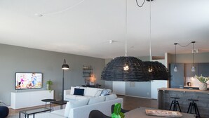 Un salon moderne avec un canapé, une table à manger et un coin cuisine à l’arrière-plan.