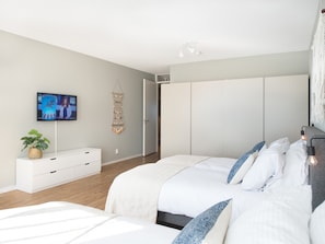 A modern bedroom with a large bed, a television, a plant, and a wardrobe. - Apartment in Den Haag for 5 Person (The Hague)