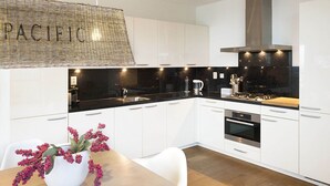 Una cocina moderna con armarios blancos, encimera negra y campana extractora de acero inoxidable.