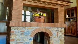 Une cheminée en pierre sur laquelle est posé un panier de fleurs.