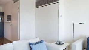 A modern, minimalist living room with a white sofa, a side table, and a floor lamp. - Modern Apartment Near the Beach (The Hague)