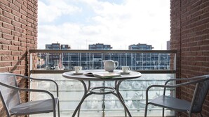 A small balcony with two metal chairs, a round table, and a white teapot. - Modern Apartment Near the Beach (The Hague)