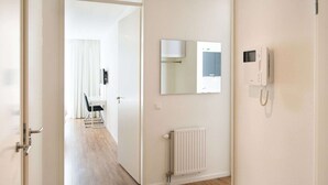 A hotel room with a wooden floor, a white radiator, a telephone, and a mirror on the wall. - Modern Apartment Near the Beach (The Hague)