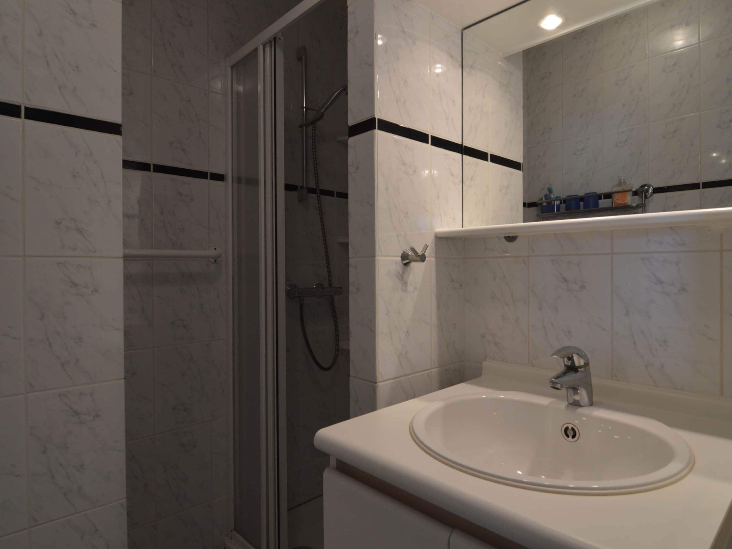 Un bagno moderno con doccia vetro, lavabo bianco e specchio sopra al lavabo.