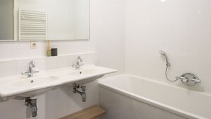 A bathroom with a white sink, a mirror, and a bathtub with a showerhead. - Apartment in Den Haag for 4 Person (The Hague)