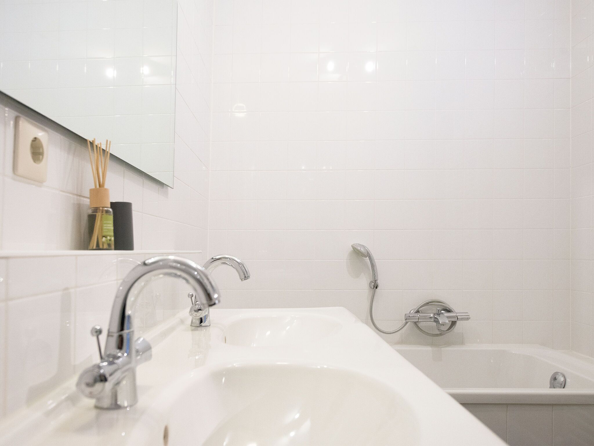 Une salle de bain avec un double lavabo, une baignoire et un miroir au-dessus du lavabo.