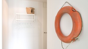 A white door with a shelf holding a brown bag and a white hanger. - Apartment in Netherlands Near the Beach (The Hague)