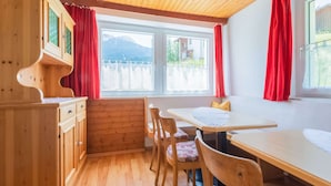 A wooden interior with a dining table, chairs, and a window with red curtains. - Chalet in Tyrol Near Ski Resort (Fliess)