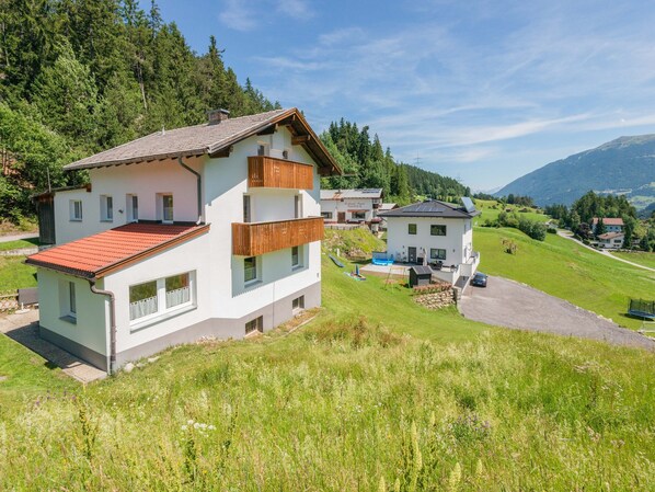 Ein zweistöckiges Haus mit rotem Ziegeldach, einem Balkon und einem kleinen Schwimmbecken.