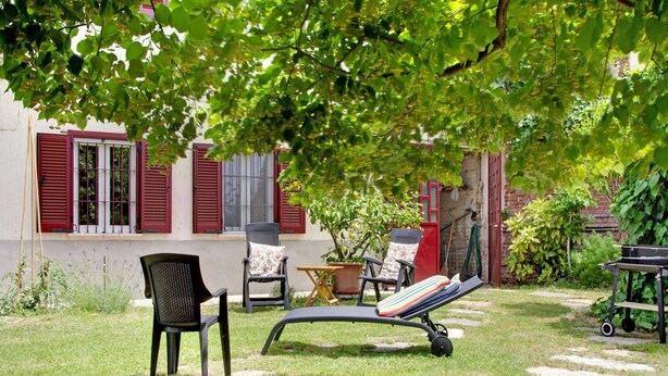 A garden with outdoor seating, including a lounge chair and two chairs, a small table, and a potted plant. - Charming Vacation House in Countryside (Moncucco Torinese)