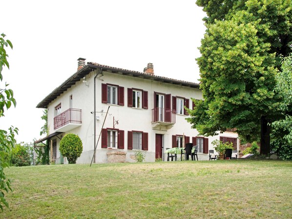 A two-story house with a balcony, a lawn, and a large tree. - Apartment in Casale With Panoramic Vineyard Views (Moncucco Torinese)