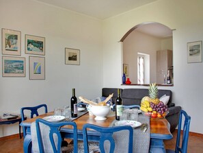 A dining area with a wooden table, blue chairs, and a fruit bowl.