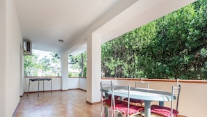 Un balcón amplio con mesa y sillas, rodeado de un seto verde exuberante.