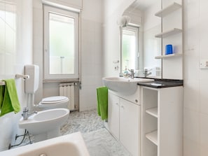 Ein modernes Badezimmer mit Toilette, Bidet, Waschbecken und Badewanne.