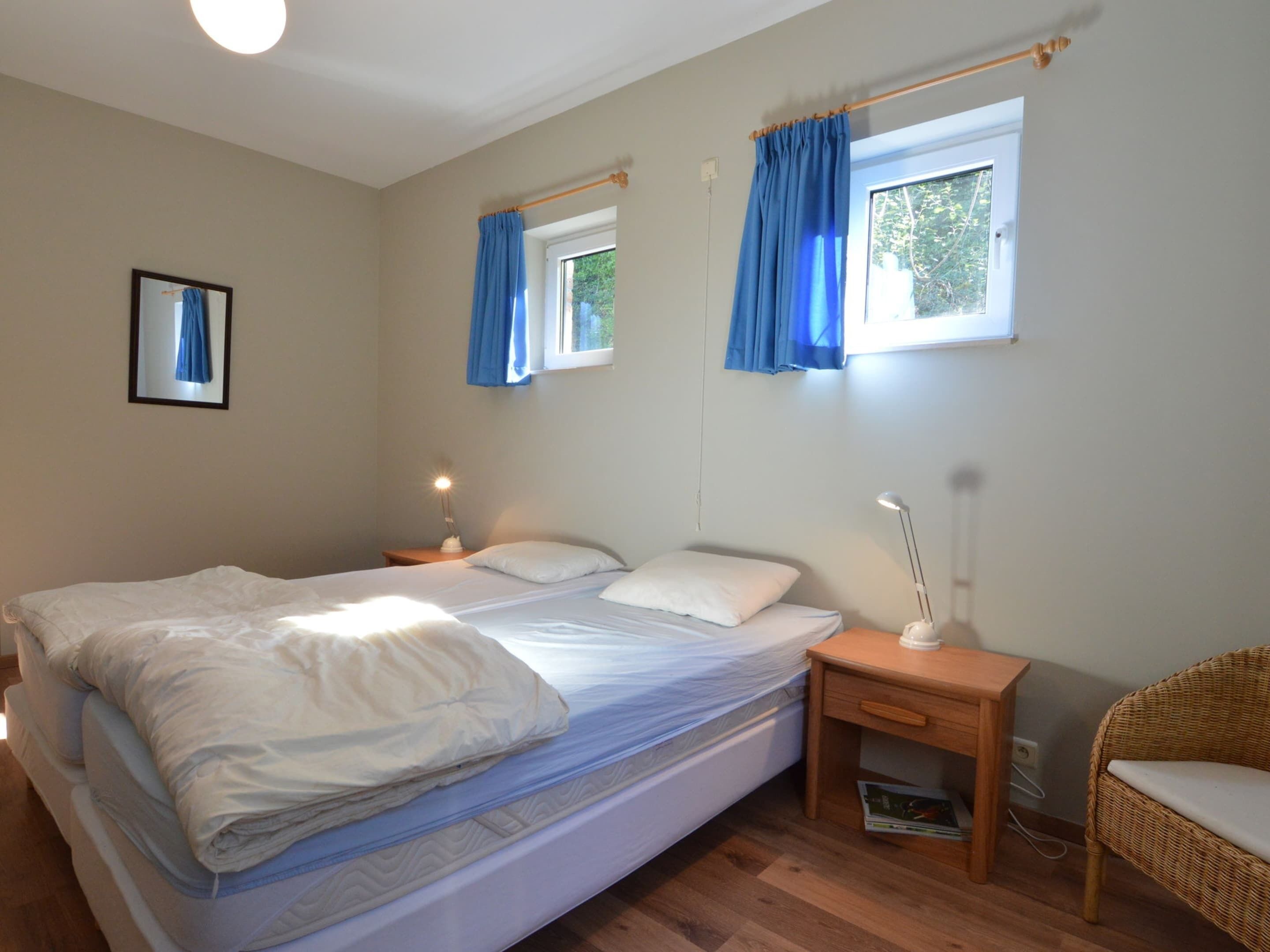 A bedroom with a bed, bedside tables, a chair, and curtains.