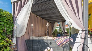 A bed with a canopy, a wicker sofa, and a small table with a colorful blanket. - Modern Holiday Home in Zadar With Terrace (Zadar)