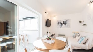 A modern living room with a round wooden table, white chairs, a white sofa, and a large window. - Modern Holiday Home in Zadar With Terrace (Zadar)