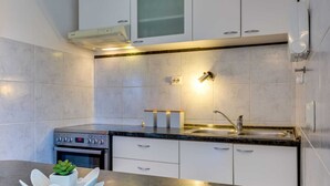 A modern kitchen with white cabinets, a stainless steel sink, and a built-in oven. - Modern Holiday Home in Zadar With Terrace (Zadar)