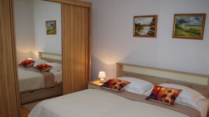 A hotel room with a large bed, a nightstand with a lamp, and two paintings on the wall. - Apartment in Croatia Near Adriatic Coast (Barban)